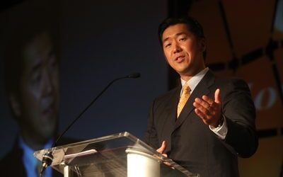 Dr. Hyun Jin Moon, in a suit and tie, giving a speech at the Global Peace Convention in Atlanta.