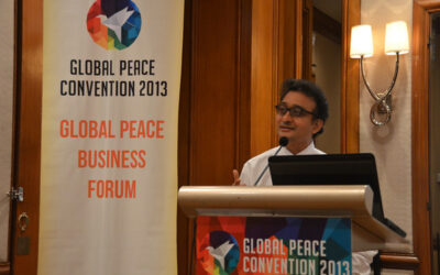 A man giving a speech at the global peace business forum.