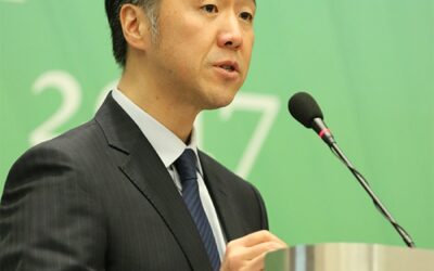 A man in a suit speaking at a podium.