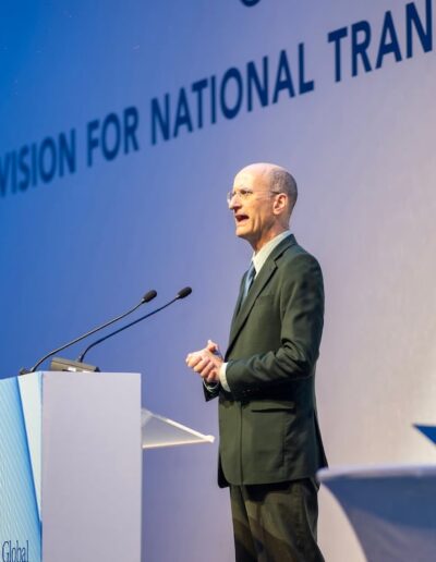 A man standing at a podium delivering a speech on national transformation at the Global Peace Convention.