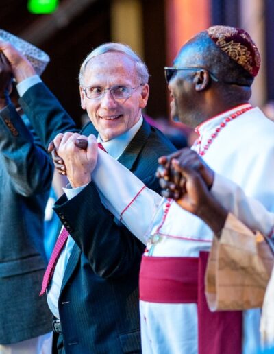 A group of men in suits and ties are waving their hands at the Global Peace Convention.