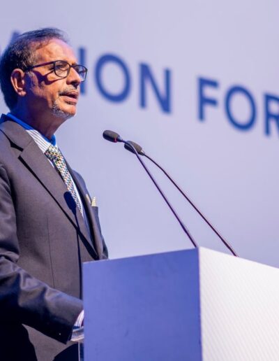 A man in a suit standing at a podium with the words vision for nations at the Global Peace Convention.