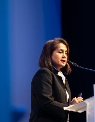 A woman speaking at the Global Peace Convention, standing at a podium.