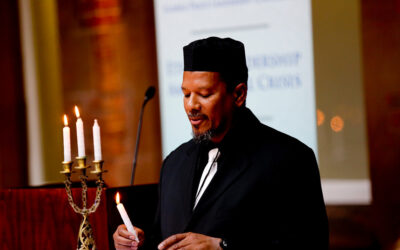 The man in the black hat is holding a candle.