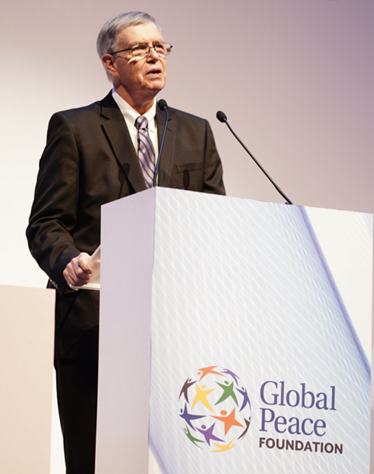 A man delivering an inspiring speech at a podium, promoting a vision for national transformation and emphasizing the importance of building a civilization of peace.