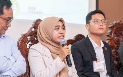 A group of young people sitting in front of a microphone engaged in peacebuilding discussions.