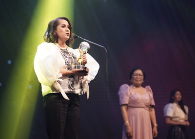 A woman holding an award at the Global Peace Convention's Awards Gala.