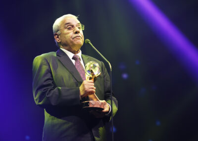 A man in a suit and tie holding an award at the Global Peace Convention's Awards Gala.