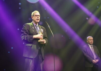 A man in a suit is holding an award at the Awards Gala.