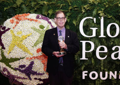 A man in a suit standing in front of a flower wall at the Global Peace Convention.
