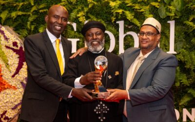 Three men posing with an award at the Global Peace Convention.