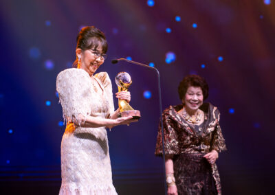 A woman holding an award on stage at the Awards Gala.